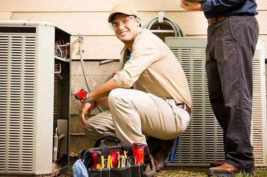 HVAC technician repairing an air conditioner unit while diagnosing the cause of a ticking noise during AC service in Canton MA.